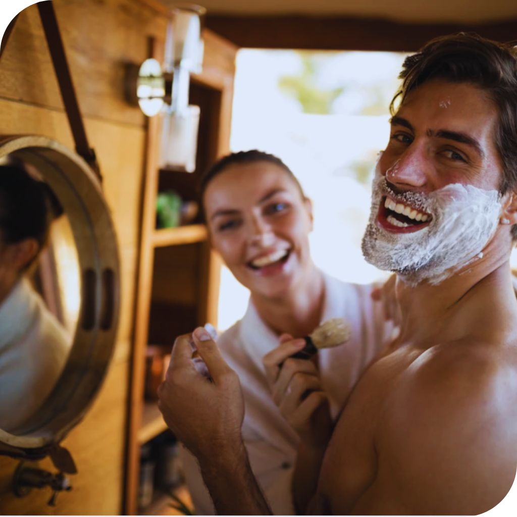 femme utilise savon pour rasage à son homme/ un souriant appliquant savon de rasage bio 